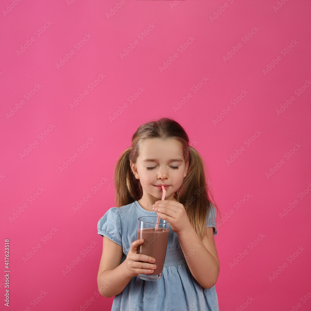 Cute little child drinking tasty chocolate milk on pink background Cute little child drinking tasty chocolate milk on pink background