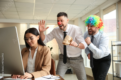 Canvas Print Men popping paper bag behind their colleague in office