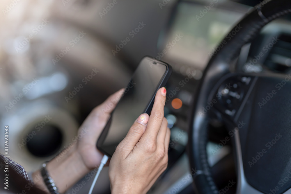 Close up of young woman hand using mobile phone in the car.