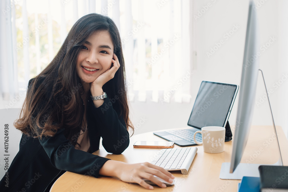 ฺBeautiful smiling Asian woman sitting at the office. Looking at the camera. ฺBeautiful smiling Asian woman sitting at the office. Looking at the camera.