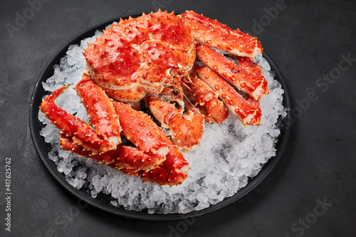 Boiled whole crab on ice over dark gray stone background