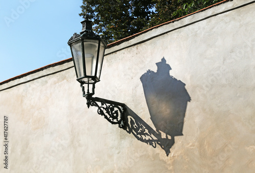 Vintage gas lamp on a plastered city wall with a shade from the sun.