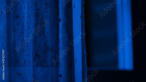 Blue window. Window with a woman. Halloween. Scary woman. Blue window with a woman.  Wind in the window. Horror. Fear. Dark window. Dark.  © Red