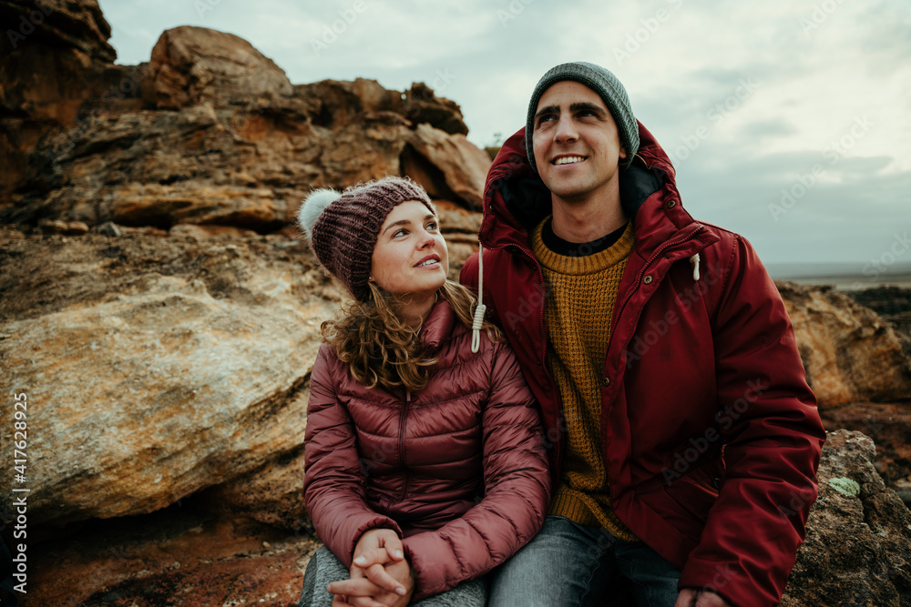 Caucasian girlfriend and boyfriend sitting on mountain smiling bonding