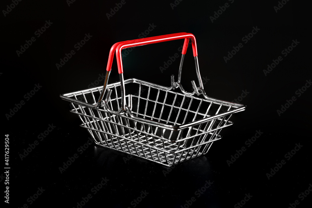 Empty metal grocery basket on a black background.