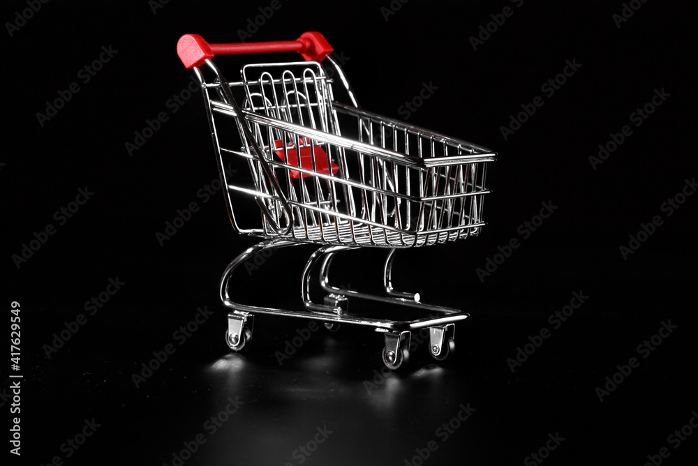Empty metal grocery cart on a black background.