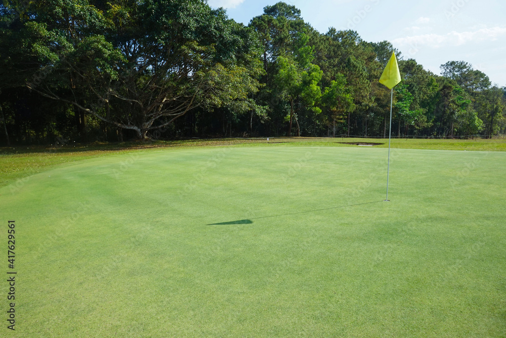 Obraz premium Background of evening golf course has sunlight shining down at golf course in Thailand. Nice scenery on a golf course at a late summer afternoon.