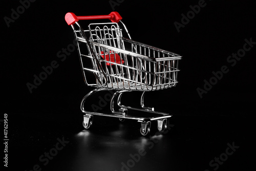 Empty metal grocery cart on a black background.