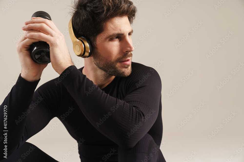 Focused athletic sportsman in headphones looking aside Focused athletic sportsman in headphones looking aside