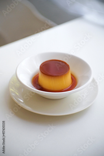 Pudding caramel custard in White ceramic bowl on table.