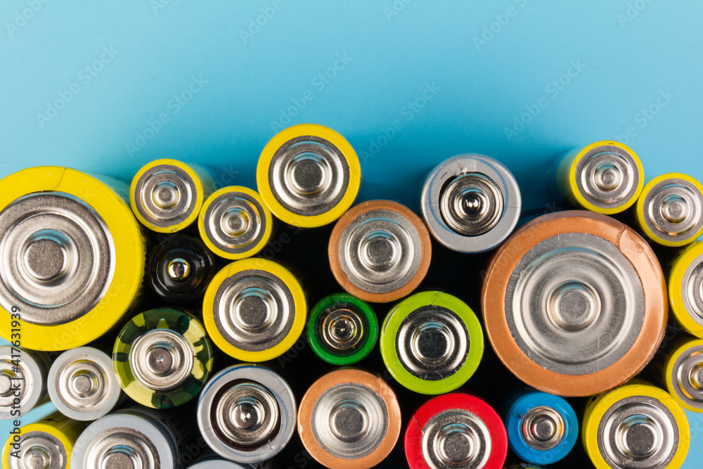 Photo of alkaline batteries on blue background. Recycling of rechargeable NiMH batteries. The different size of accumulators. Copy space.
