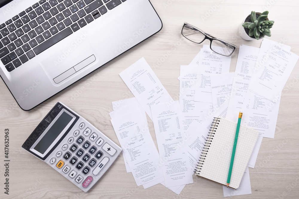 Bills and calculator with checks for goods and services.. calculator to calculate bills at the table in office. Calculation of costs. Bills and calculator with checks for goods and services.. calculator to calculate bills at the table in office. Calculation of costs.