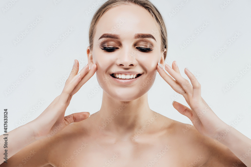 Close up of an attractive woman who touches her face, she has oily and radiant skin, freshness and beauty. White background with place for advertising inscription Close up of an attractive woman who touches her face, she has oily and radiant skin, freshness and beauty. White background with place for advertising inscription