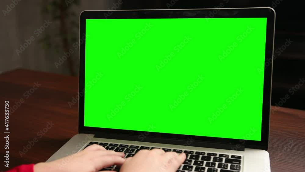 Over the shoulder little boy use laptop with green screen mock-up template on a display. Close-up shot typing on notebook keyboard. Computer online e-learning Over the shoulder little boy use laptop with green screen mock-up template on a display. Close-up shot typing on notebook keyboard. Computer online e-learning