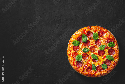 Pepperoni Pizza with Mozzarella cheese, salami, Tomato sauce, pepper, Spices. Italian pizza on Dark grey black slate background
