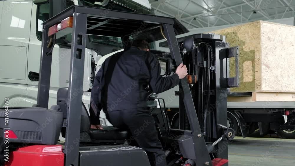Mechanic operator works on warehouse loader in large repair shop. Transportation of spare parts for passenger cars in service station on forklift. loader operator works in a logistics car repair shop