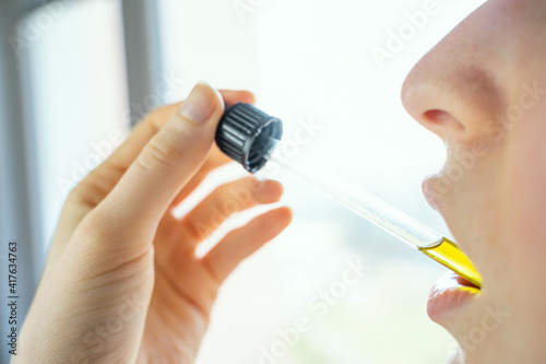 Woman Taking CBD Oil Under Tongue from tincture