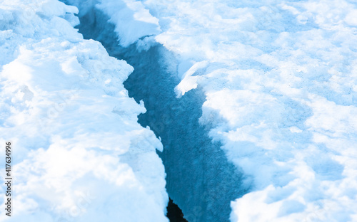 Large clean crack in sea ice with white snow on the top and clear blue ice beneath. Close up. photo