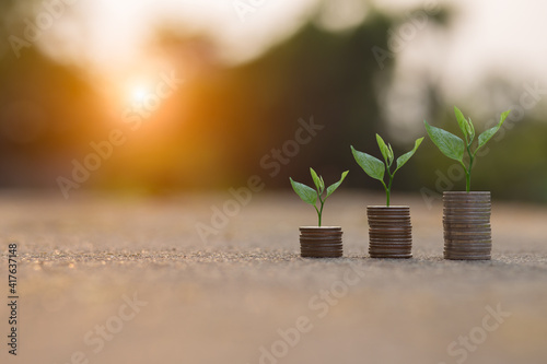 Saving money by hand puting coins in jug glass on nature background