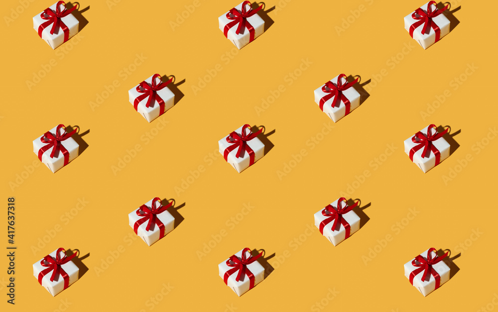 Gift pattern. Orange seamless background. Special day greeting. Holiday congratulation. Symmetrical composition of presents in white boxes with red ribbon bows isolated on bright yellow.