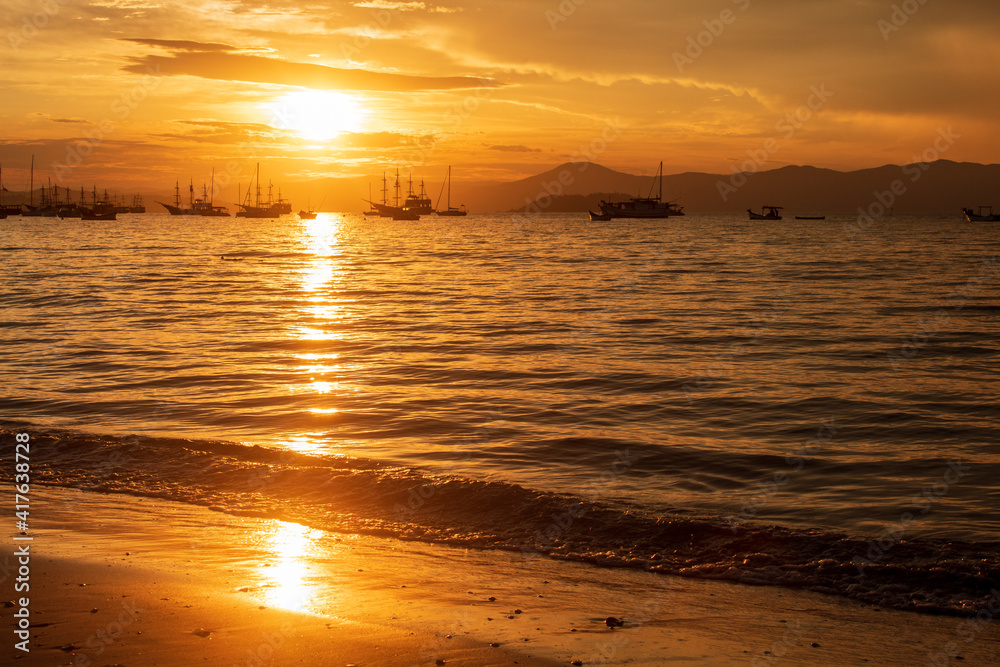 Sunset on a tropical beach with pirate boats in the background located on the beach of Cachoeira do Bom Jesus, Canasvieras, Ponta das Canas, Florianopolis, Santa Catarina, Brazil, Florianópolis