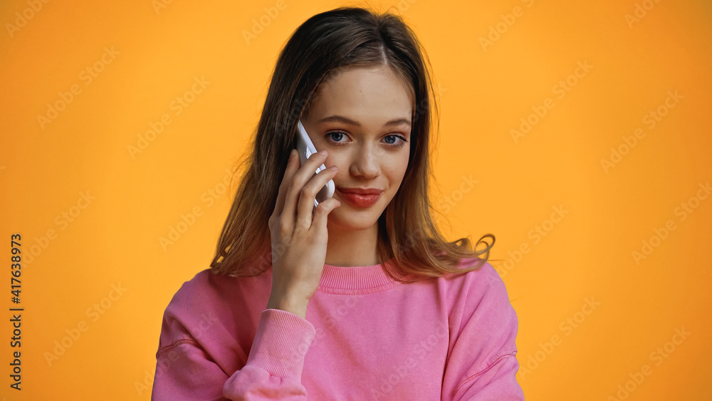 cheerful teenage girl looking at camera while talking on smartphone isolated on yellow cheerful teenage girl looking at camera while talking on smartphone isolated on yellow