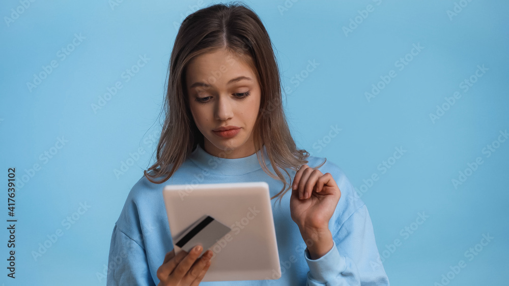 teenage girl in sweatshirt holding credit card and digital tablet isolated on blue teenage girl in sweatshirt holding credit card and digital tablet isolated on blue