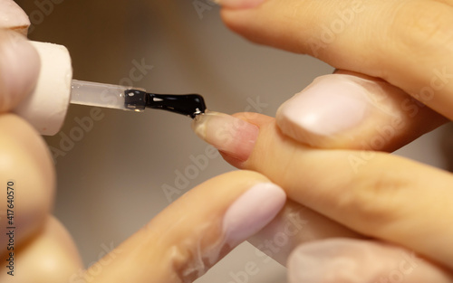 Manicure artist making nail polishing with brush and tools.