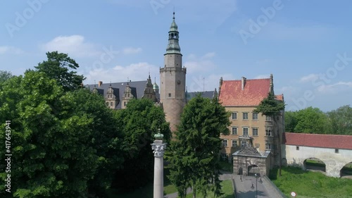Castle of the Dukes of Oleśnica in Oleśnica, Poland. Drone video on a sunny summer day. Historic buildings with a clock tower.