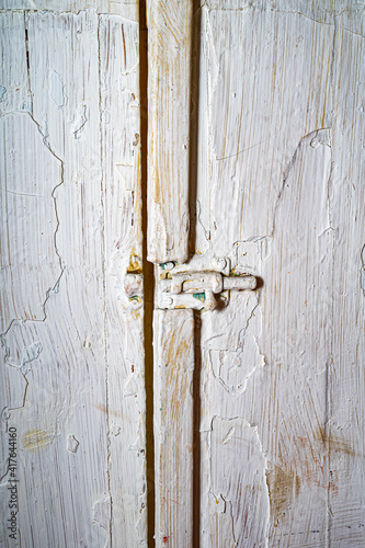 old swing doors covered in cracked white paint. Old doors with a latch in the closet