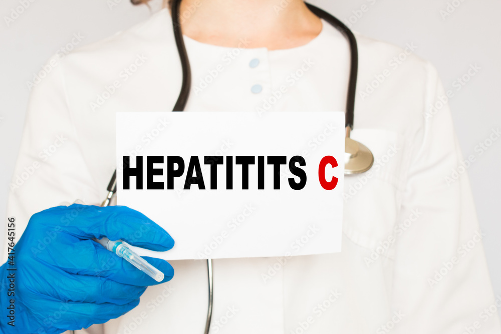 The doctor's blue - gloved hands show the word HEPATITIS C - . a gloved hand on a white background. Medical concept. the medicine The doctor's blue - gloved hands show the word HEPATITIS C - . a gloved hand on a white background. Medical concept. the medicine