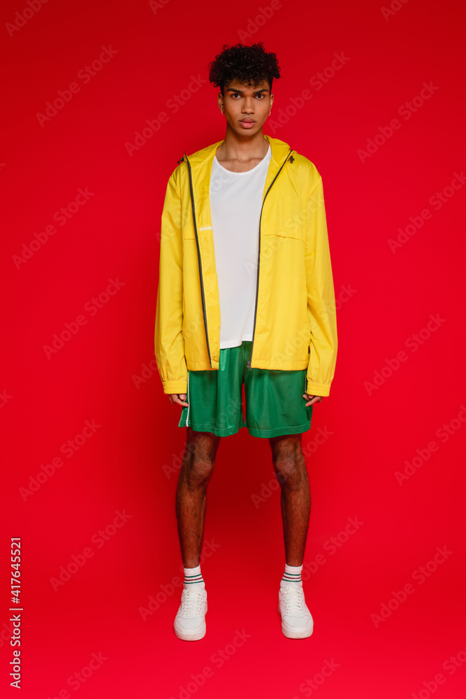 full length of stylish african american man posing on red
