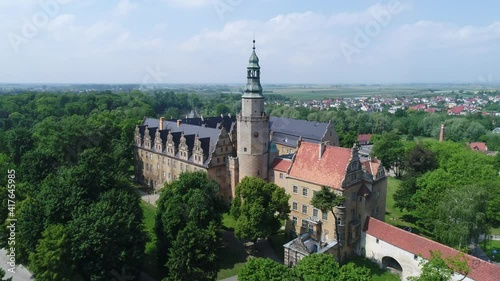 Castle of the Dukes of Oleśnica in Oleśnica In Poland from a great height on a video from a drone. Historical building surrounded by a park with lots of trees. Sunny summer day.