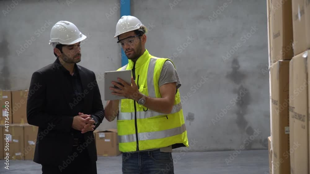 Executive business man or owner walking with warehouse manager visit storage and using tablet computer checking list and inventory of Cargo box in warehouse