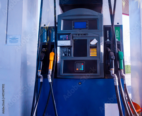 Detail of a petrol pump in a petrol station.Close up on fuel nozzle in oil dispenser with gasoline and diesel in service gas station. Pattern petrol pump gun filling. Blue, green, red, golden colors.