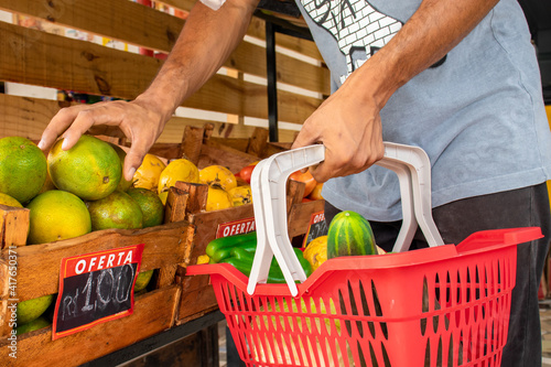 Homem segurando cesta de frutas e legumes no mercado.