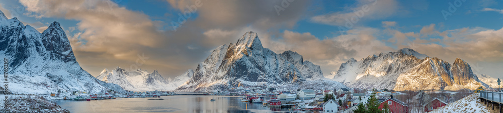Sunset view of the picturesque fishing village of Reine with illuminated mountain peaks in the background, Lofoten, Norway.