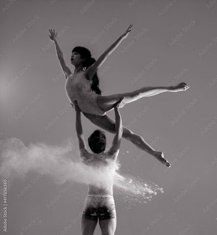 Two ballet dancers perform dance against background of white flour cloud in air. Two ballet dancers perform dance against background of white flour cloud in air.
