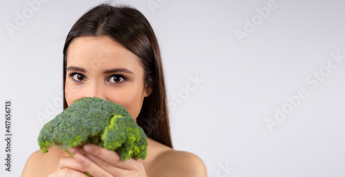 Portrait of a beautiful woman with broccoli, isolated on white background. Vegetarian food concept