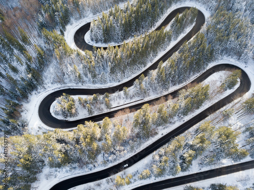 Winding road aerial view by drone. Brasov, Romania. There are huge snow mountains and long winding road in this area. This is a great place to drive and stop during a road trip.