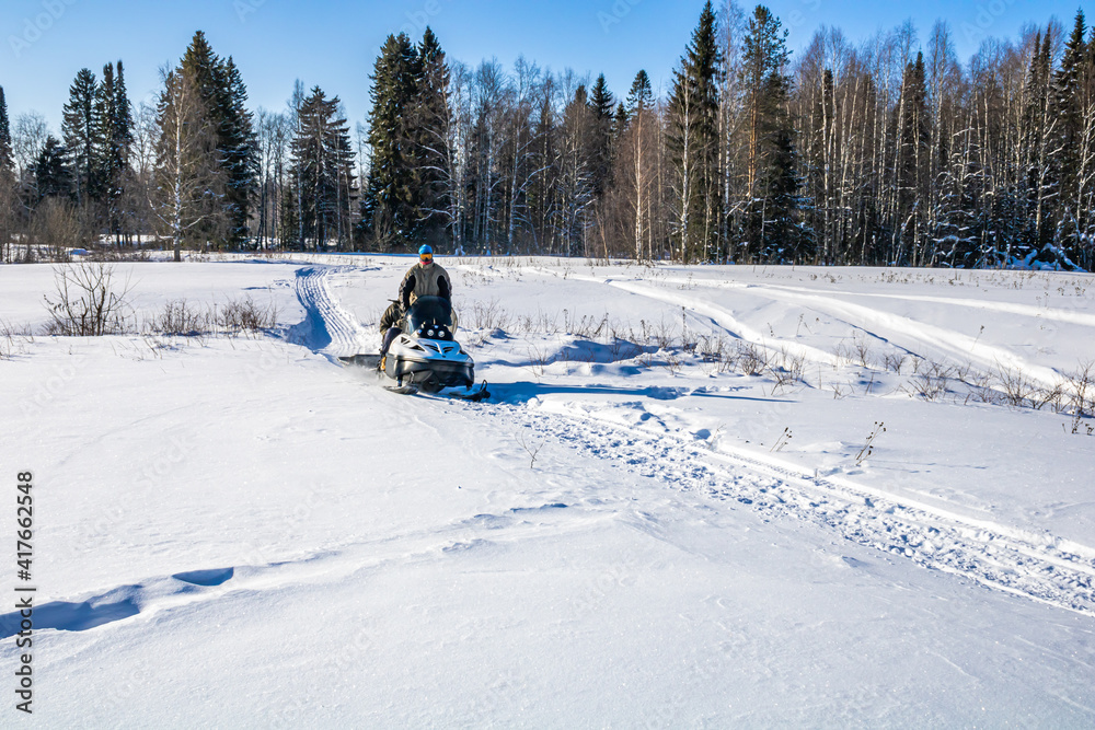 Fototapeta premium Family winter walks on a snowmobile in nature.