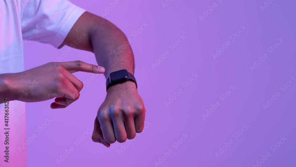 Fototapeta premium African Male Using Smartwatch With Black Blank Screen Under Purple Neon Light