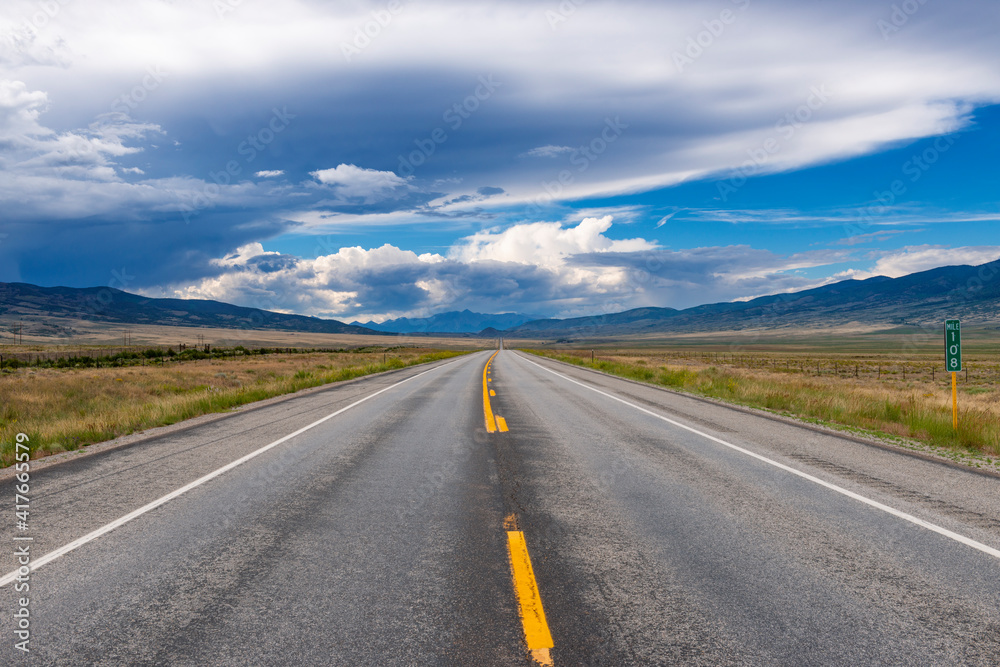 Scenic view of an empty road with mountains on the background, in the State of Colorado, USA; Concept for travel and road trip in the USA Scenic view of an empty road with mountains on the background, in the State of Colorado, USA; Concept for travel and road trip in the USA