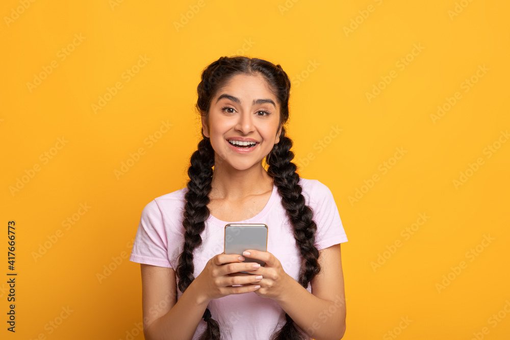 Indian woman using smartphone isolated on yellow background Indian woman using smartphone isolated on yellow background
