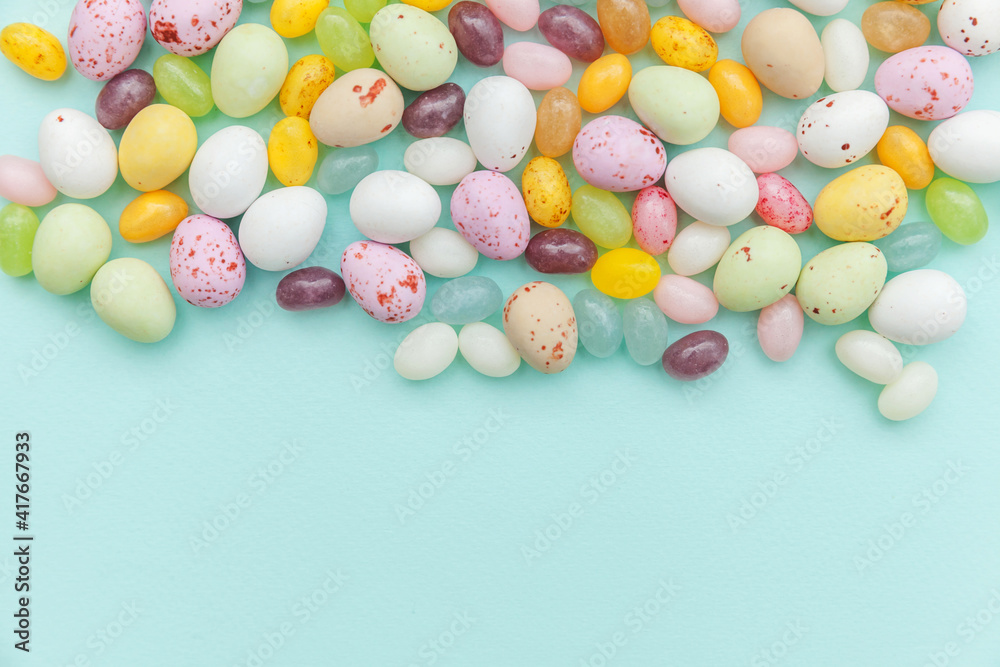 Happy Easter concept. Preparation for holiday. Easter candy chocolate eggs and jellybean sweets isolated on trendy pastel blue background. Simple minimalism flat lay top view copy space.