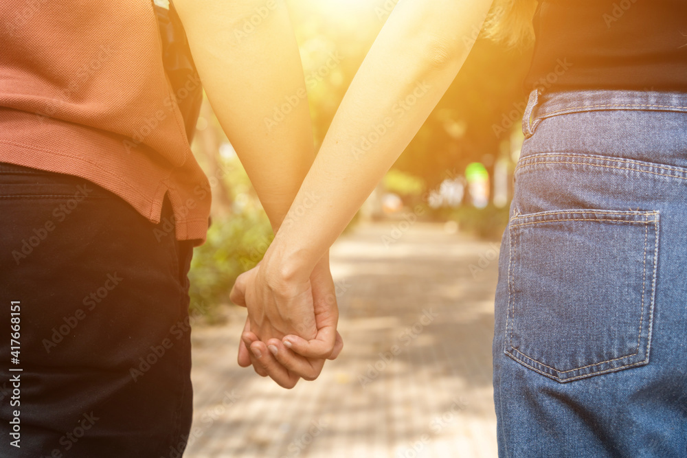 Couple hold hands in the autumn or summer park on sunset. Closeup of loving couple holding hands while walking. Couple hold hands in the autumn or summer park on sunset. Closeup of loving couple holding hands while walking.