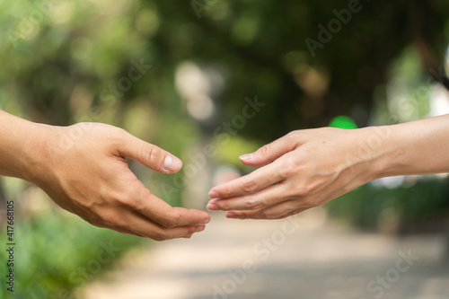 Concept of human relation, community, togetherness, teamwork, love, symbolism, culture and history. Hand of male and female reaching to each other. Nature background. Selective focus.