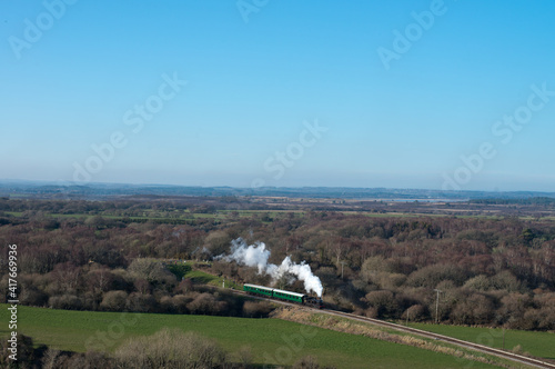 a vintage steam locomotive pulls a short train through scenic landscape on the Swanage heritage railway in the UK