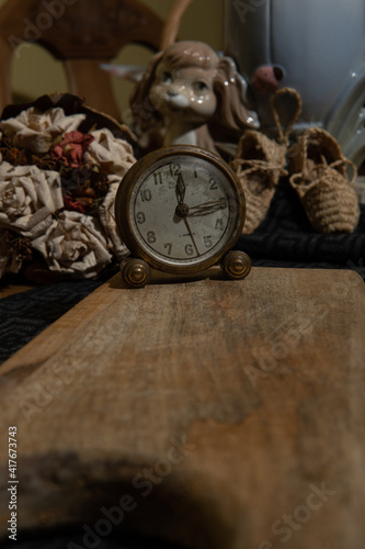 Wooden table still life with dried roses and antique clock