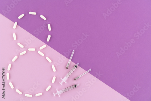 Figure 8 of white tablets in capsules and syringes with needles on a lilac, purple background. Flat lay. Copy space. World Women's Day, March 8. The concept of medicine and healthcare. Number 8